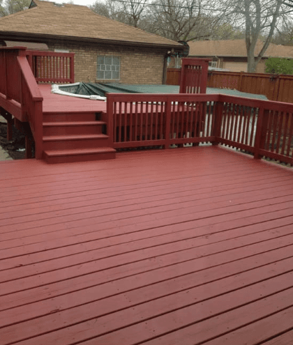 Multi-level reddish-brown wooden deck with stairs and railings next to a covered pool.