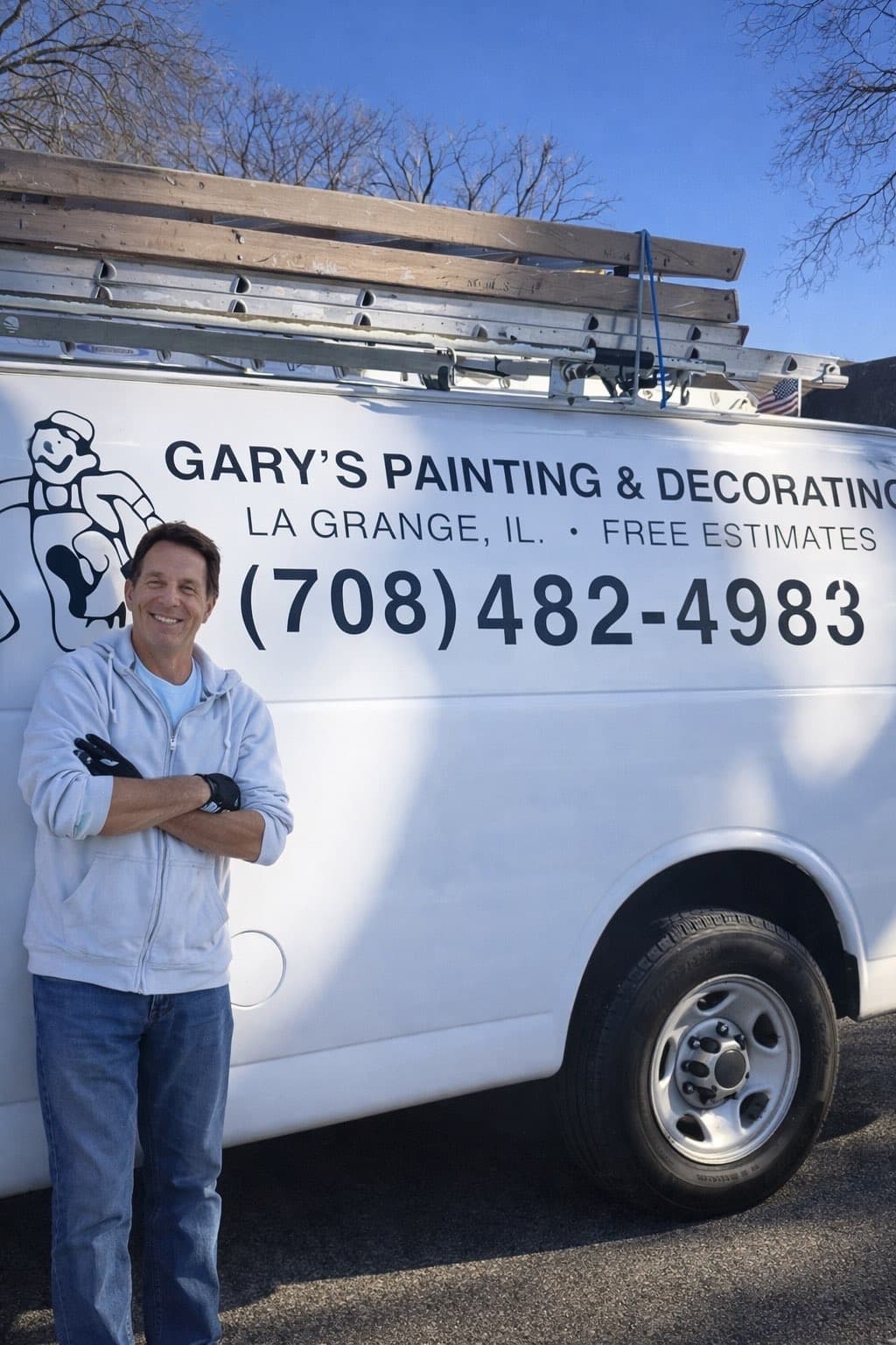 Smiling man stands with arms crossed beside a white Gary's Painting and Decorating van.